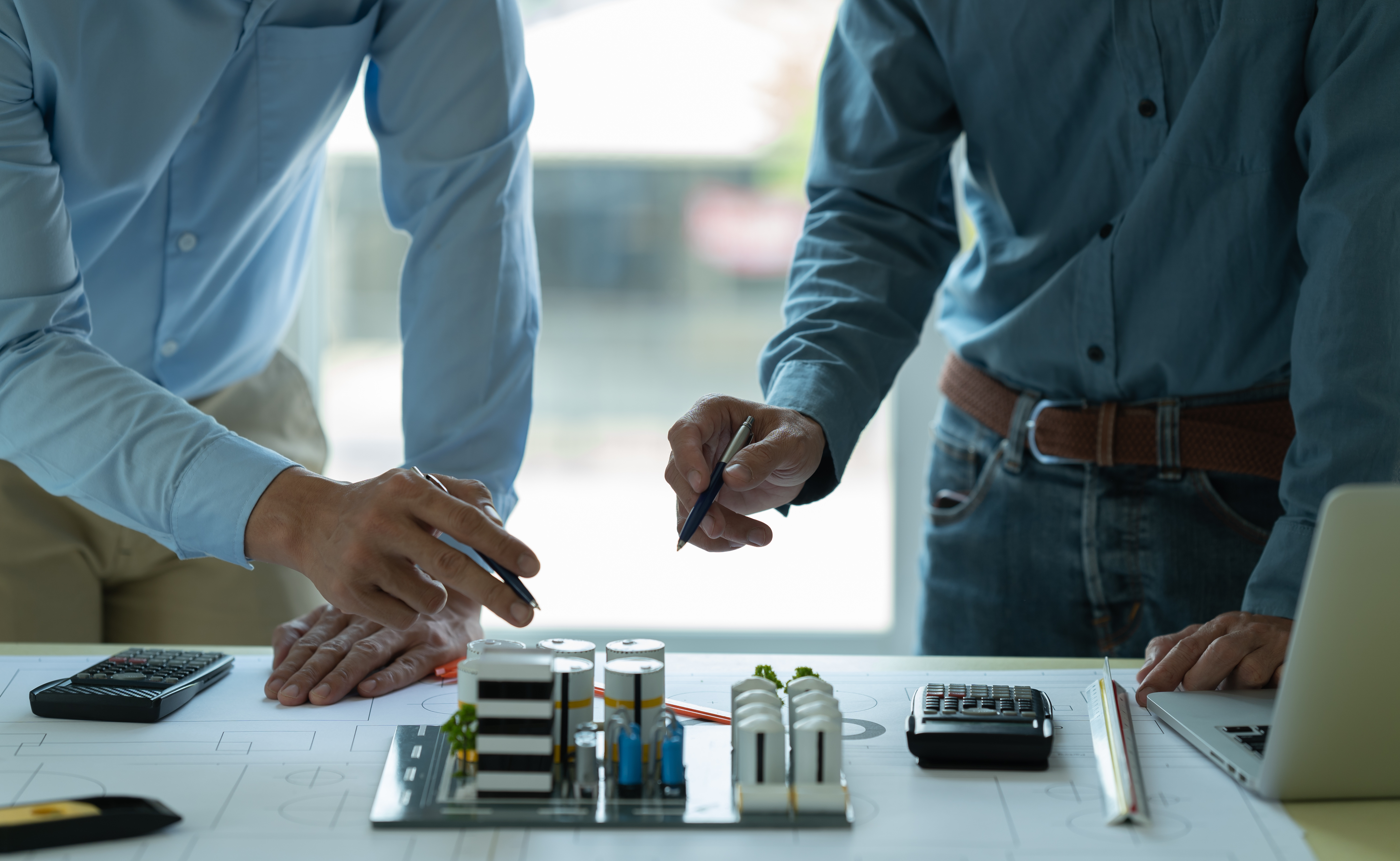 Two architects planning the blueprint for an oil plant's layout.